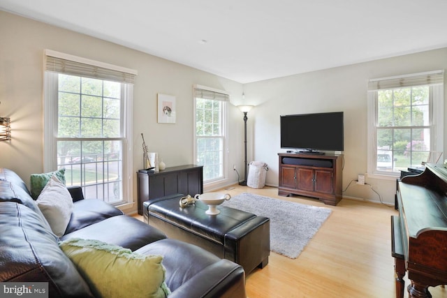 living room featuring healthy amount of natural light, light wood-type flooring, and baseboards