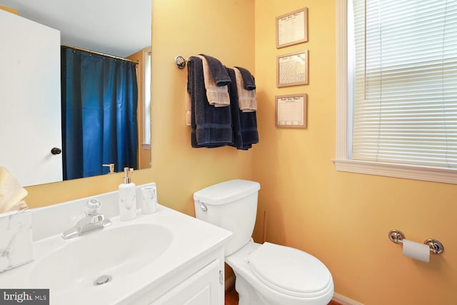 bathroom featuring toilet, vanity, and curtained shower
