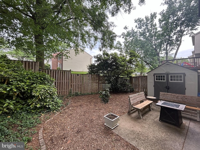 view of patio / terrace with a fire pit, a storage unit, a fenced backyard, and an outdoor structure