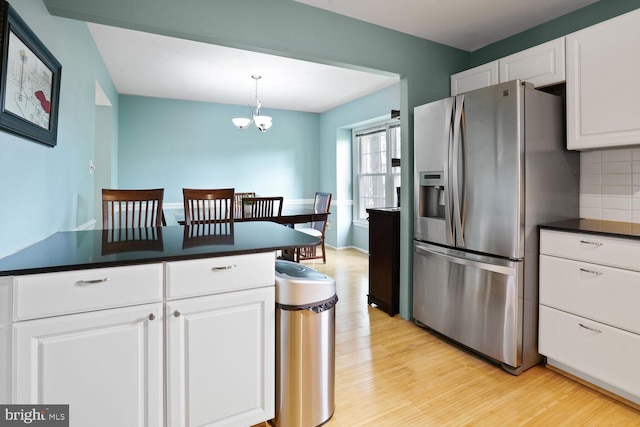 kitchen featuring stainless steel fridge with ice dispenser, light wood-style flooring, white cabinetry, backsplash, and dark countertops