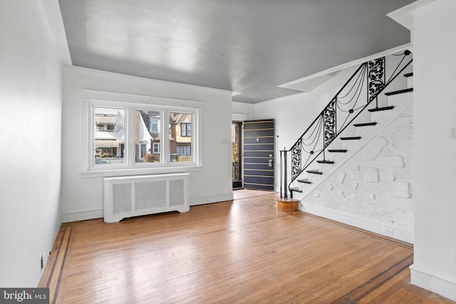 entrance foyer with stairs, radiator, baseboards, and wood finished floors
