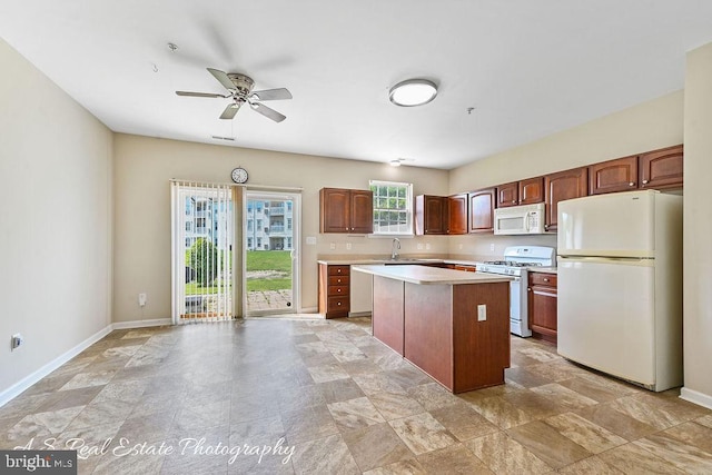 1007 Whispering Ponds Ct, Salisbury, MD 21804 - kitchen with white appliances, a kitchen island, light countertops, ceiling fan, and baseboards