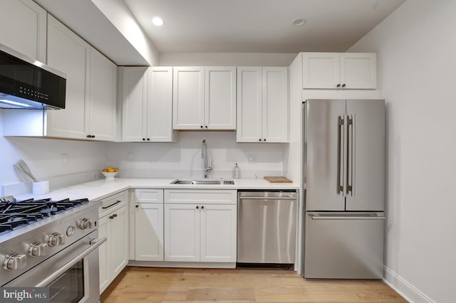 kitchen with light wood-style flooring, a sink, stainless steel appliances, white cabinetry, and recessed lighting
