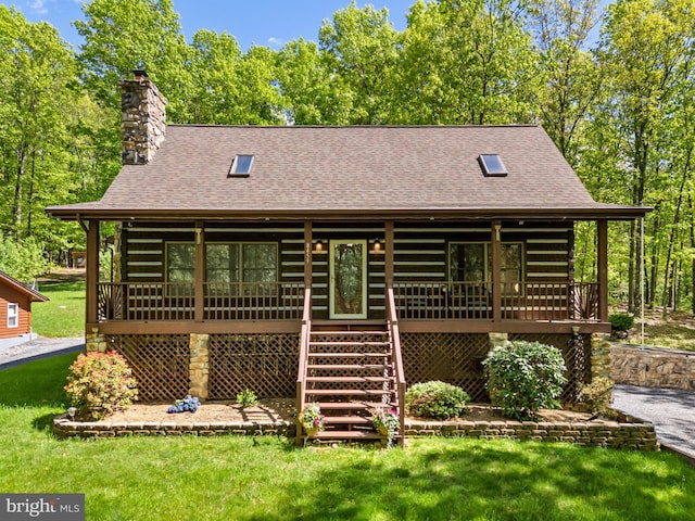 rear view of property featuring roof with shingles, a porch, a lawn, and log siding