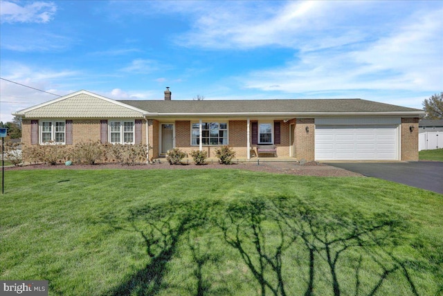 single story home with an attached garage, a chimney, a front lawn, brick siding, and driveway