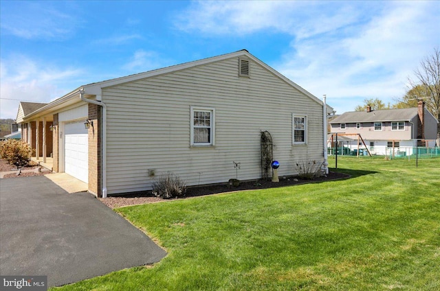 view of home's exterior featuring a garage, fence, a lawn, and aphalt driveway
