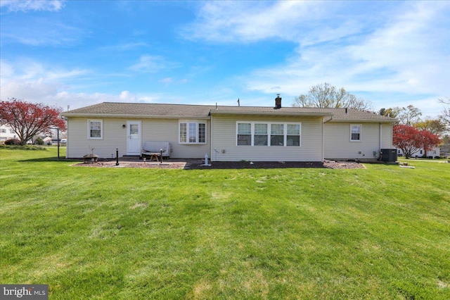 rear view of property featuring a patio area, a chimney, central AC, and a lawn