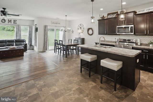 kitchen featuring appliances with stainless steel finishes, a sink, ceiling fan, dark brown cabinetry, and decorative backsplash