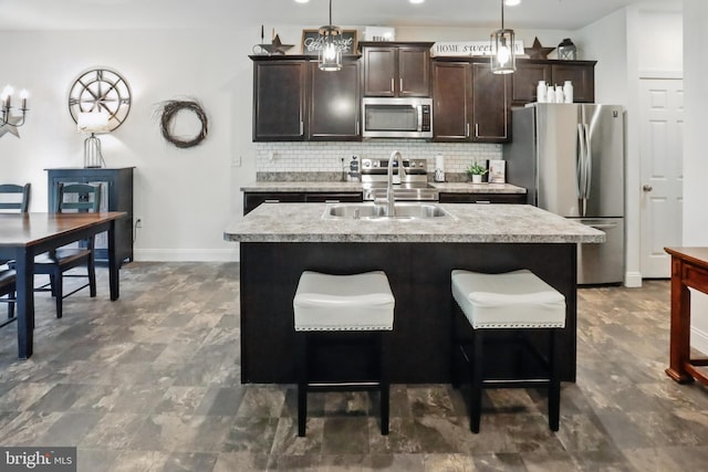 kitchen with stainless steel appliances, a sink, tasteful backsplash, light countertops, and an island with sink