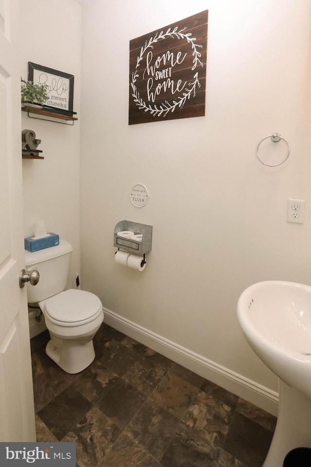 half bathroom featuring toilet and baseboards