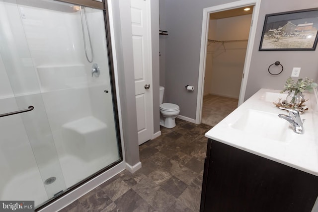 full bathroom with toilet, a shower stall, a walk in closet, and double vanity