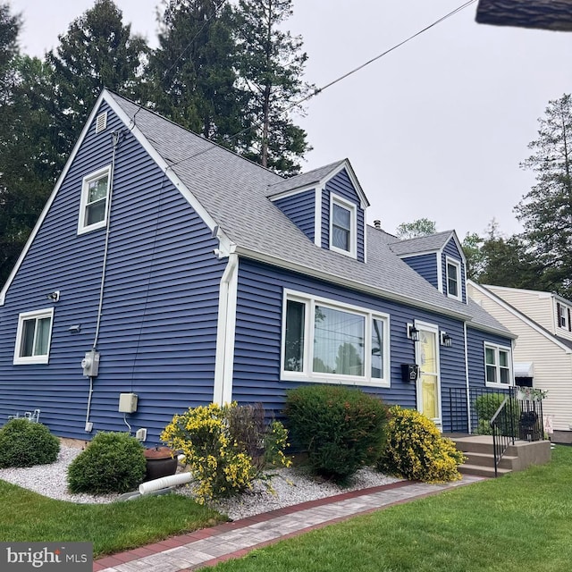 cape cod-style house featuring a front lawn and a shingled roof