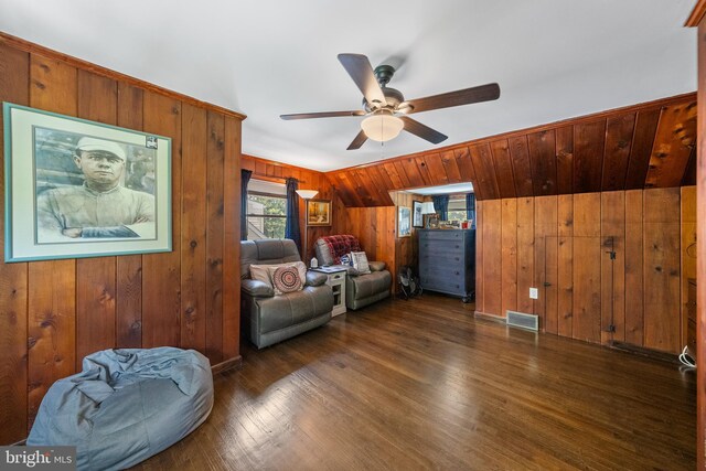 living area with ceiling fan, wooden walls, and dark wood-style floors