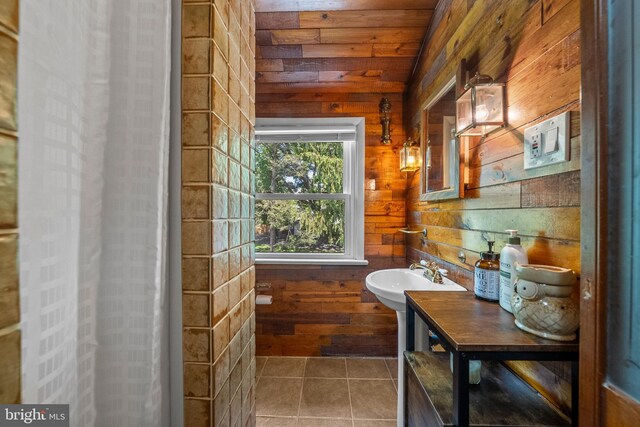 bathroom featuring a sink, wooden walls, and tile patterned floors