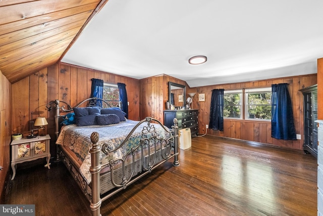 bedroom featuring wood walls, multiple windows, wood finished floors, and vaulted ceiling