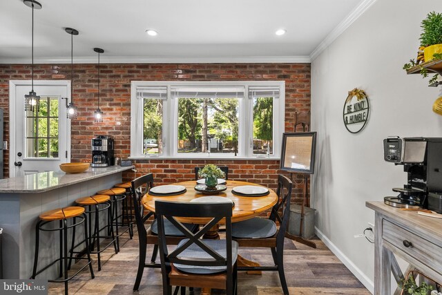 dining area featuring healthy amount of natural light, ornamental molding, baseboards, wood finished floors, and brick wall