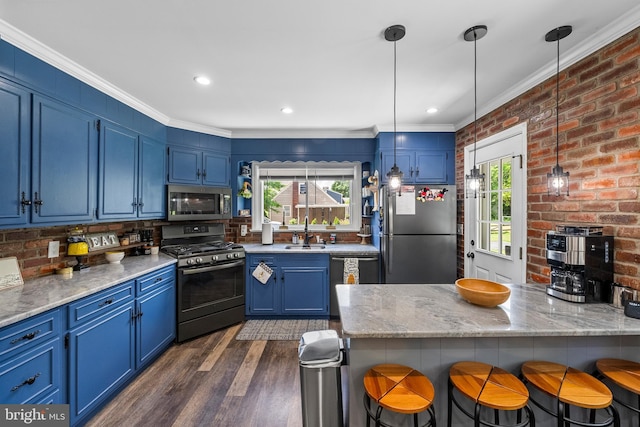 kitchen with appliances with stainless steel finishes, blue cabinets, a sink, ornamental molding, and a kitchen bar