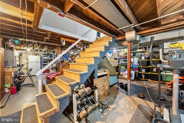 unfinished basement with freestanding refrigerator and stairway