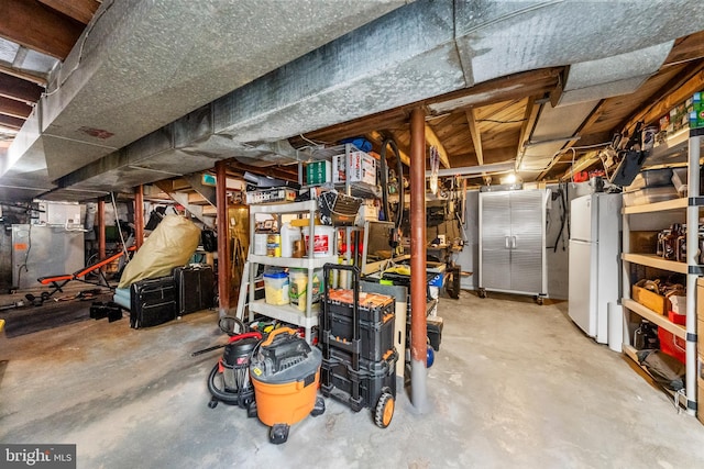 unfinished below grade area with freestanding refrigerator and heating unit