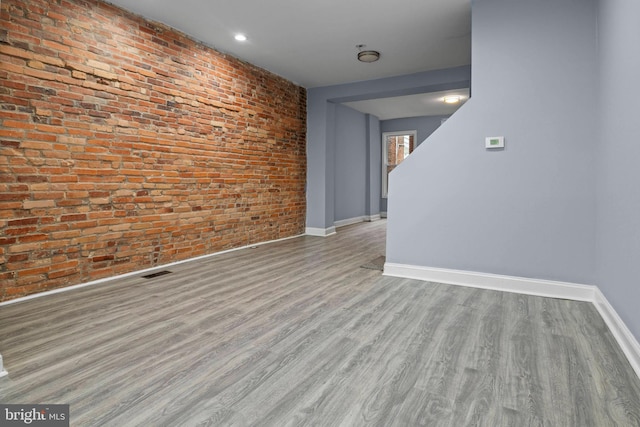 524 N Loudon Ave, Baltimore, MD 21229 - spare room featuring baseboards, brick wall, visible vents, and wood finished floors