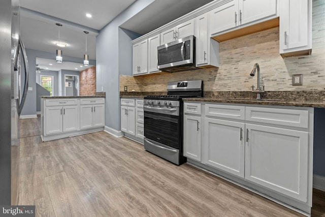 524 N Loudon Ave, Baltimore, MD 21229 - kitchen with light wood finished floors, a sink, decorative backsplash, white cabinets, and appliances with stainless steel finishes