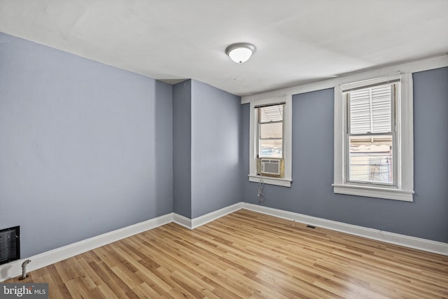 empty room featuring light wood-type flooring, visible vents, and baseboards