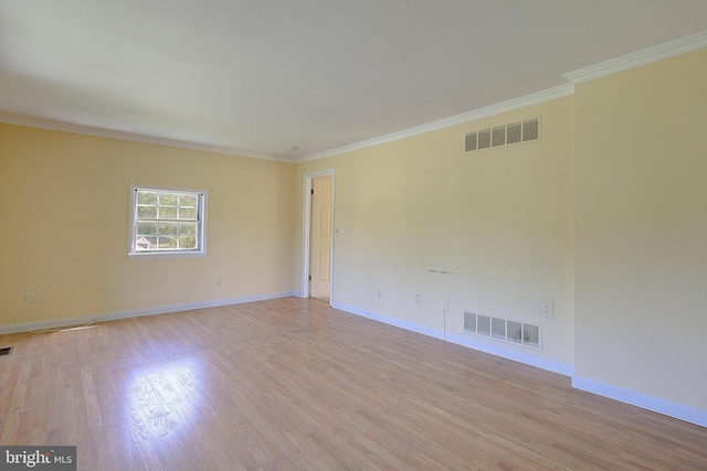 spare room with ornamental molding, light wood-style floors, and baseboards