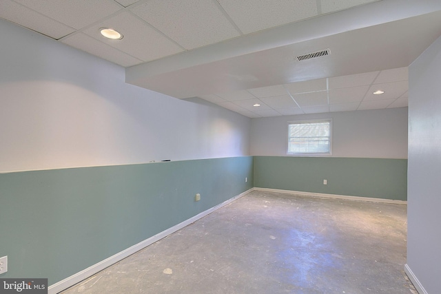 empty room with a drop ceiling, concrete flooring, baseboards, and recessed lighting