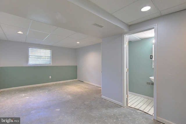 empty room with a paneled ceiling, baseboards, and unfinished concrete flooring