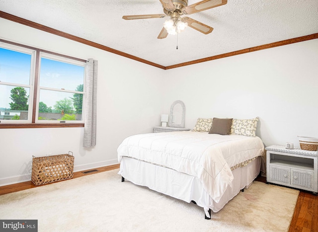 bedroom with wood finished floors, ornamental molding, a textured ceiling, baseboards, and a ceiling fan