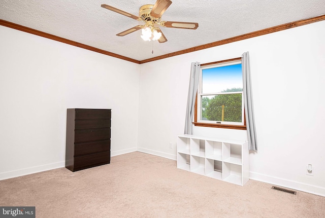 carpeted spare room featuring a textured ceiling, crown molding, ceiling fan, and baseboards