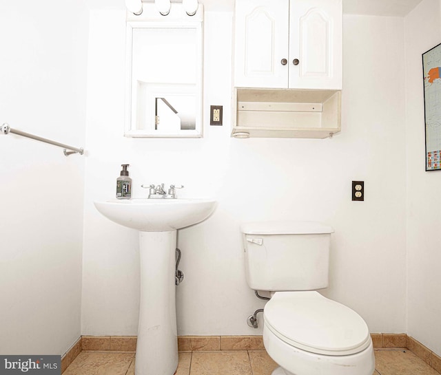 half bathroom featuring baseboards, toilet, and a sink