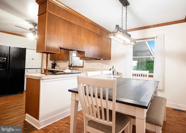 kitchen featuring black fridge with ice dispenser, crown molding, a ceiling fan, light countertops, and backsplash