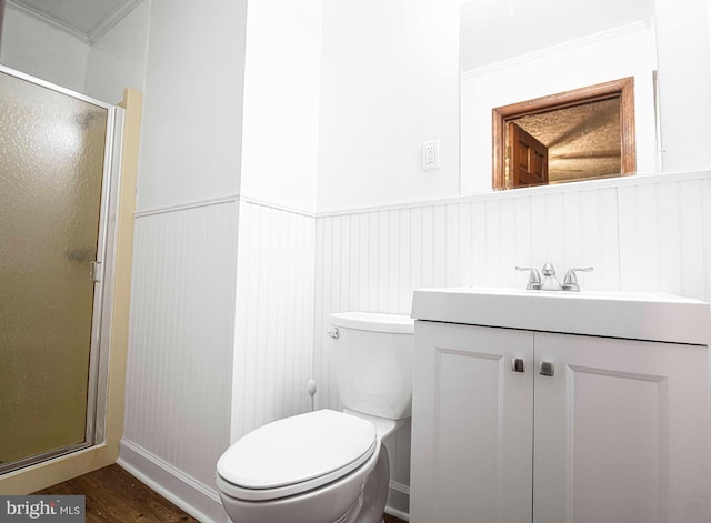 bathroom with a shower stall, a wainscoted wall, wood finished floors, toilet, and vanity