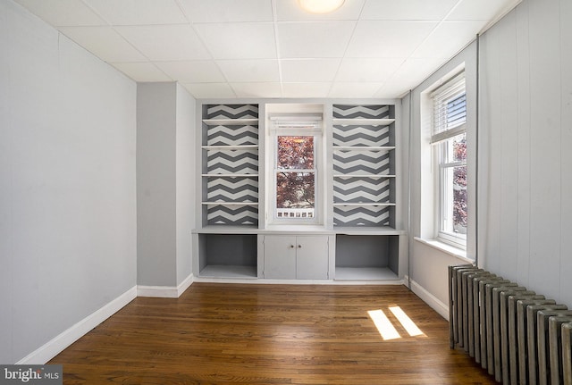unfurnished room featuring radiator heating unit, dark wood finished floors, and baseboards