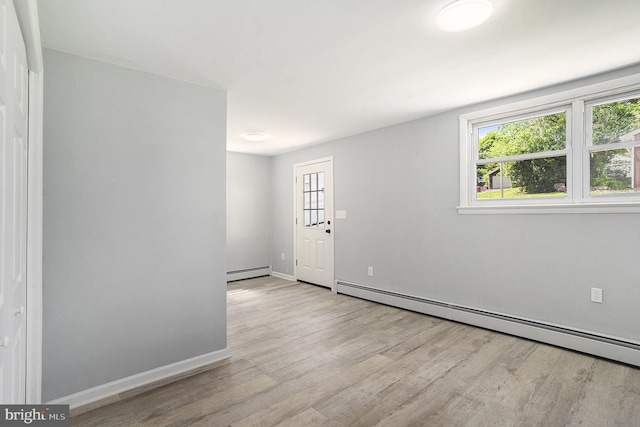 spare room with baseboard heating, wood finished floors, and plenty of natural light