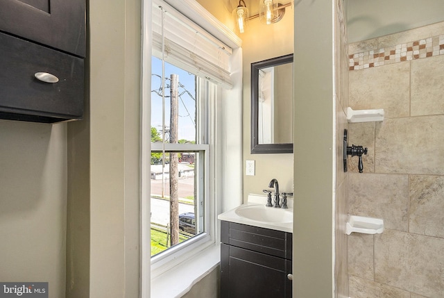 bathroom featuring plenty of natural light, a tile shower, and vanity
