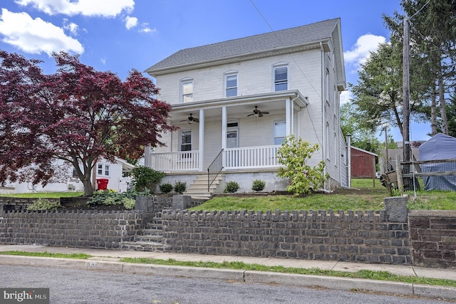 view of front facade featuring ceiling fan, a porch, stairway, and fence