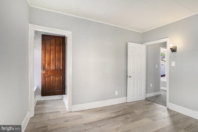 unfurnished room featuring wood finished floors, crown molding, and baseboards