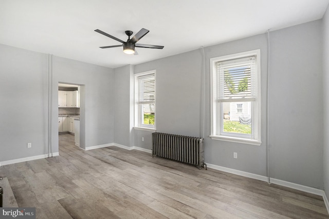 unfurnished bedroom with radiator, light wood-style floors, and baseboards