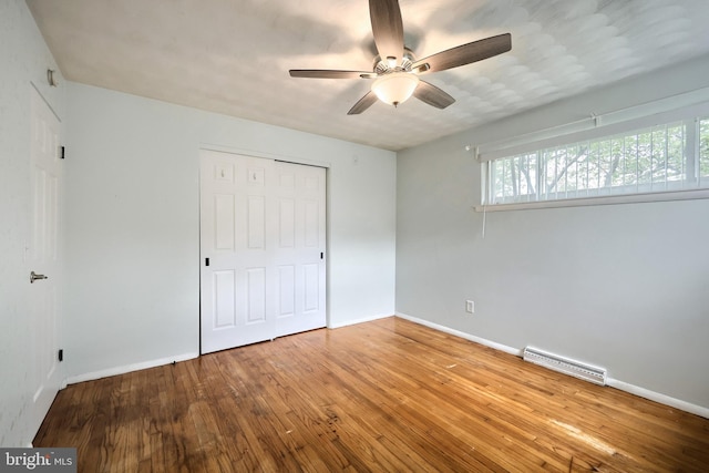 unfurnished bedroom featuring wood-type flooring, baseboards, a closet, and ceiling fan