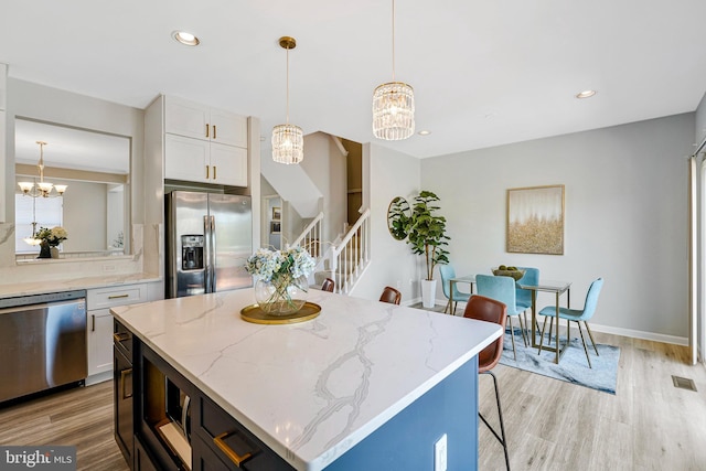 kitchen featuring an inviting chandelier, stainless steel appliances, light wood-type flooring, and white cabinets