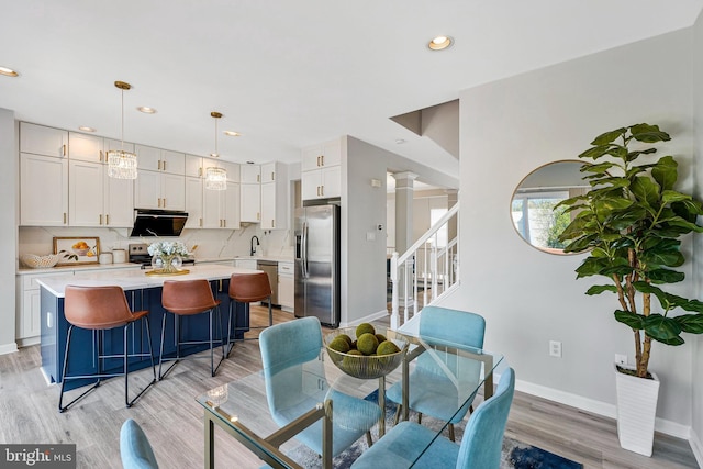 dining area featuring baseboards, light wood-style floors, recessed lighting, and stairway