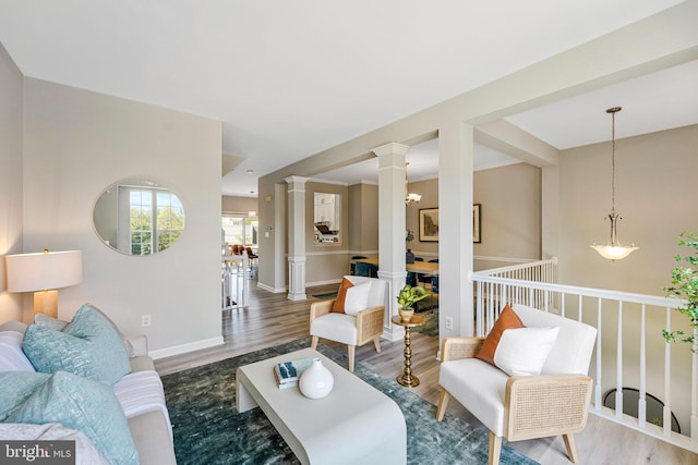 living area with baseboards, decorative columns, and wood finished floors