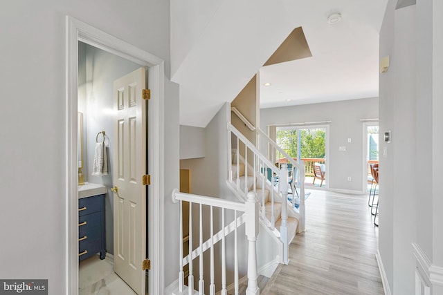 hall featuring stairs, baseboards, light wood-type flooring, and recessed lighting