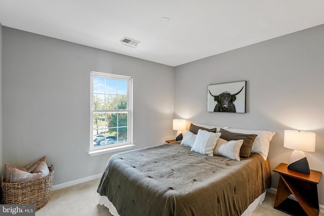 bedroom with baseboards, visible vents, and light colored carpet