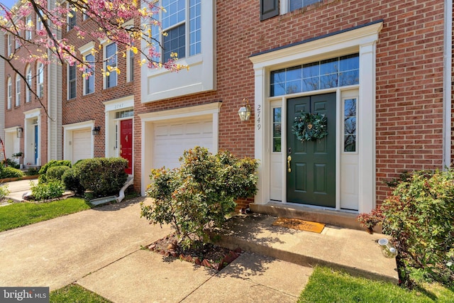 property entrance with an attached garage and brick siding