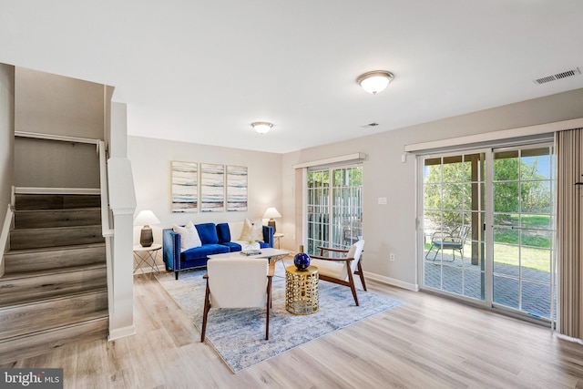 living room featuring visible vents, wood finished floors, baseboards, and stairs
