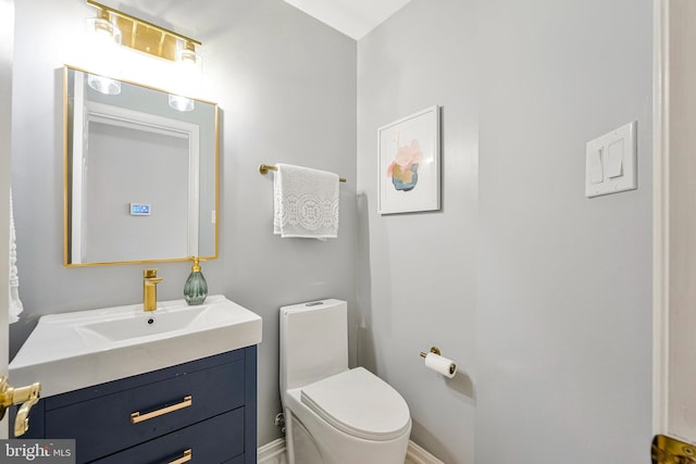half bath with vanity, toilet, and baseboards