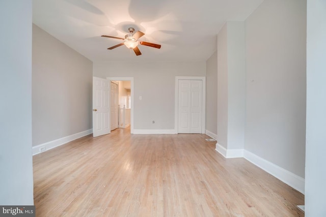spare room featuring light wood-type flooring, baseboards, and ceiling fan